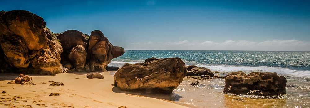 A beach with large boulders on the coast.